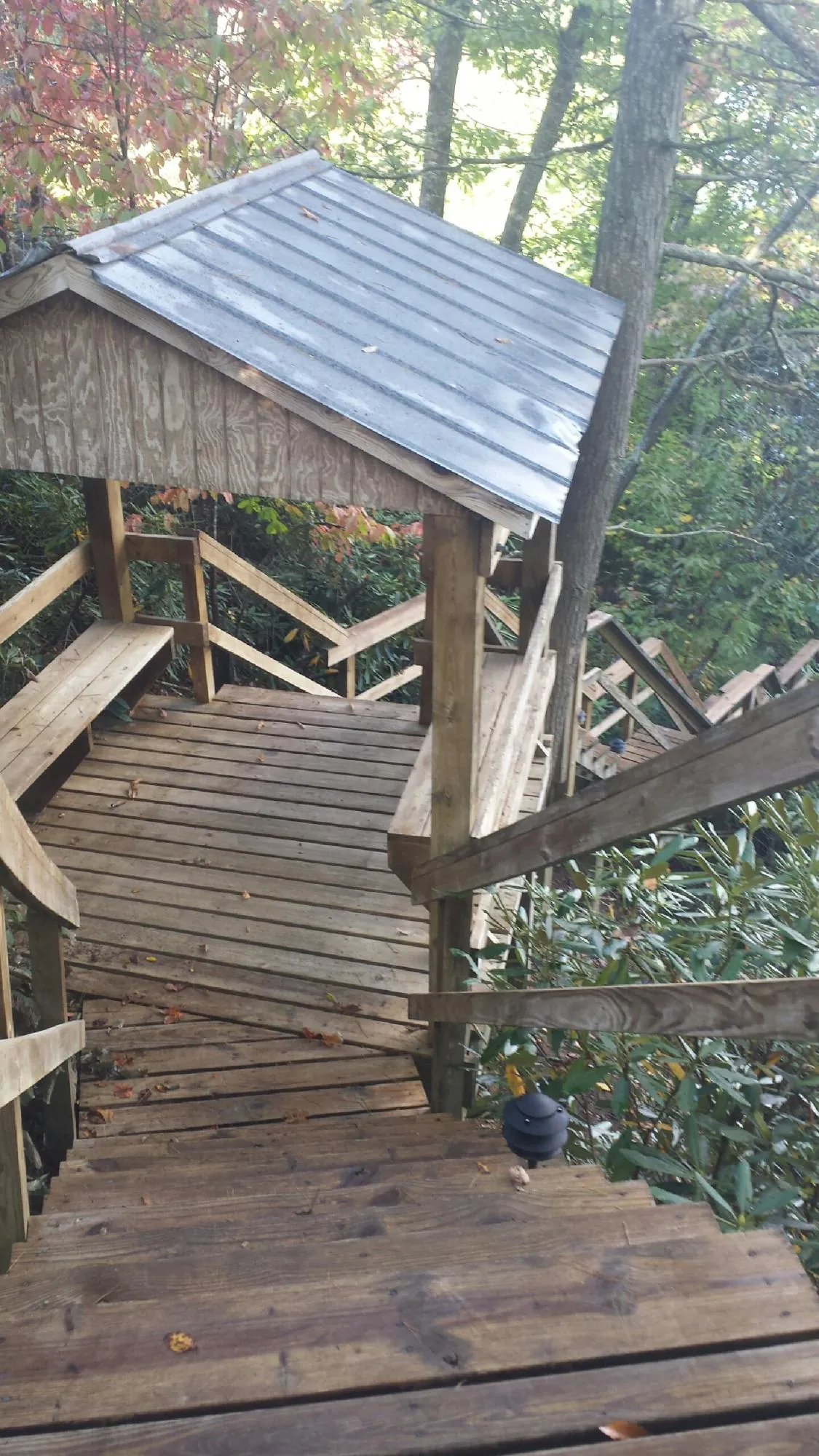 Metal roofed shelter over wooden steps on a wooded walkway — Skylight Repair & Installation work by our crew in Canaan
